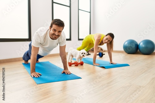 Young hispanic couple training yoga at sport center.