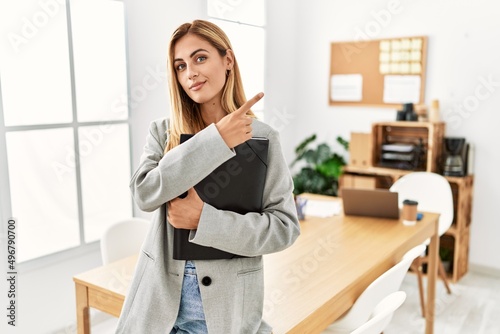 Blonde business woman at the office pointing with hand finger to the side showing advertisement, serious and calm face © Krakenimages.com