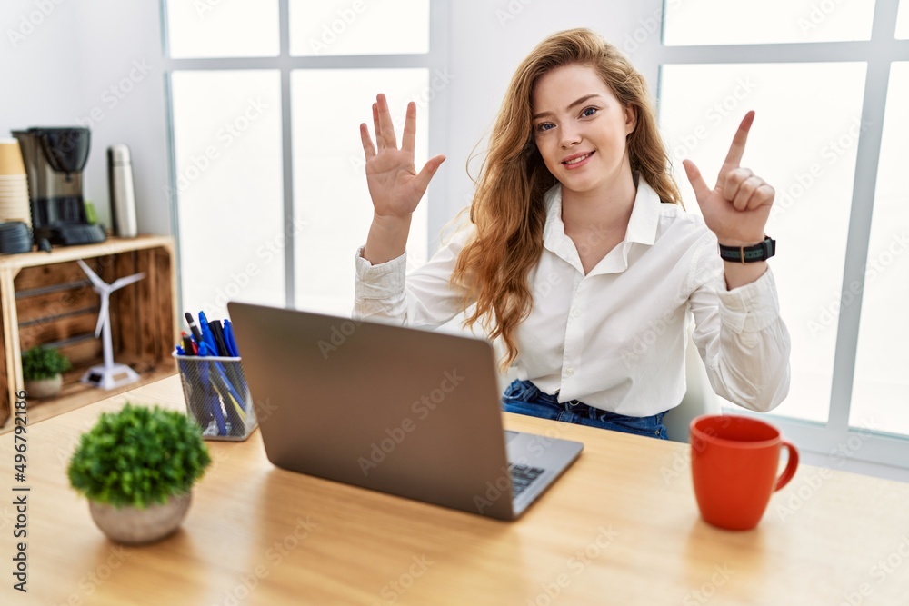 Young caucasian woman working at the office using computer laptop showing and pointing up with fingers number seven while smiling confident and happy. Young caucasian woman working at the office using computer laptop showing and pointing up with fingers number seven while smiling confident and happy.