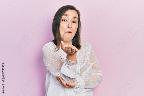 Middle age hispanic woman wearing casual clothes looking at the camera blowing a kiss with hand on air being lovely and sexy. love expression. © Krakenimages.com