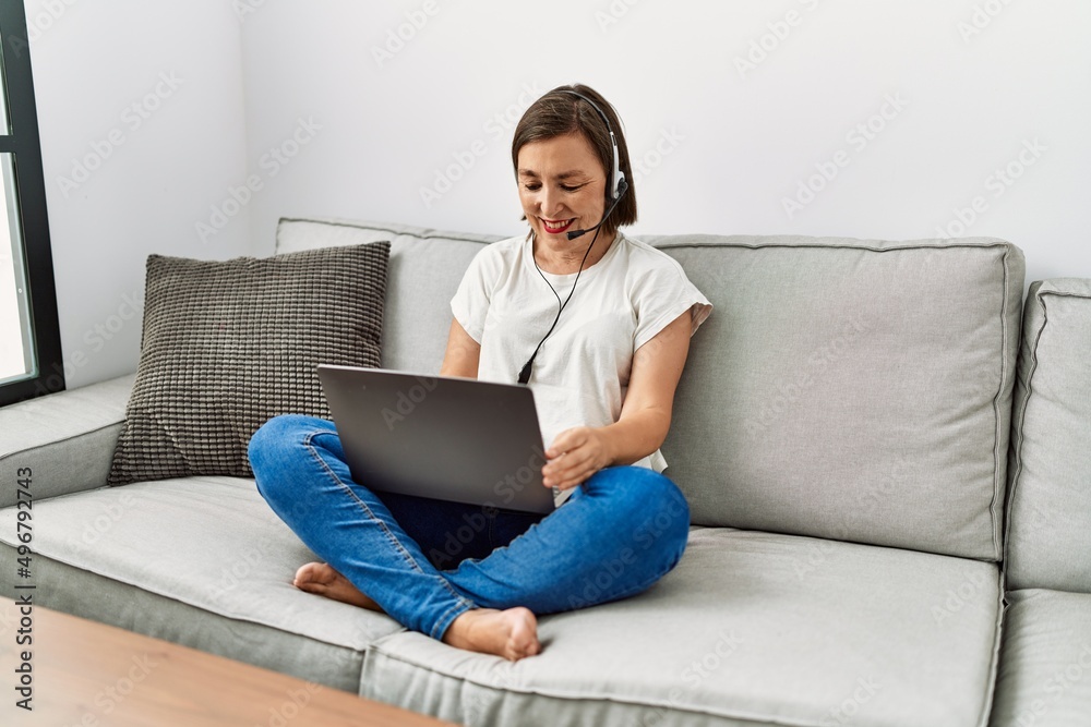 Middle age hispanic woman sitting on the sofa wearing headset at home Middle age hispanic woman sitting on the sofa wearing headset at home