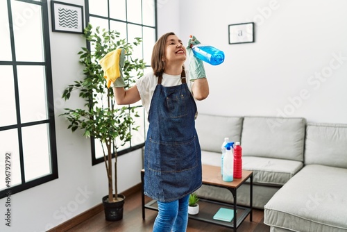 Middle age hispanic woman working as housekeeper dancing at home
