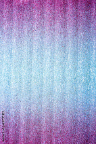 Texture of folded metallic crepe paper colored in pink to blue neon gradient
