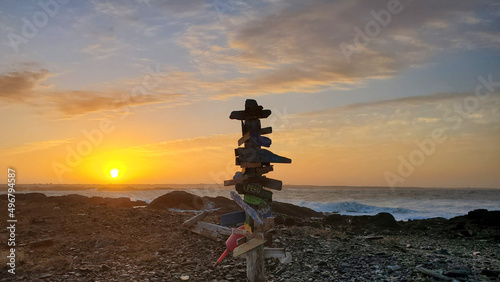 Wooden pole with direction signs against the sunset. Cape Forchu Lighthouse, Nova Scotia, Canada. photo