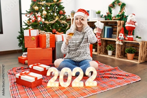 Young beautiful woman with white modern hair standing by christmas tree celebrating 2022 new year smiling happy doing ok sign with hand on eye looking through fingers