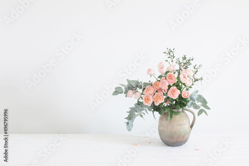 bouquet of peony roses in ceramic jug on white background