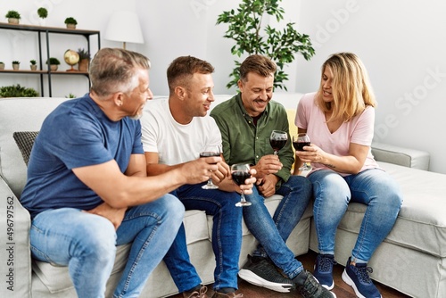 Group of middle age friends toasting with glass of wine at home.