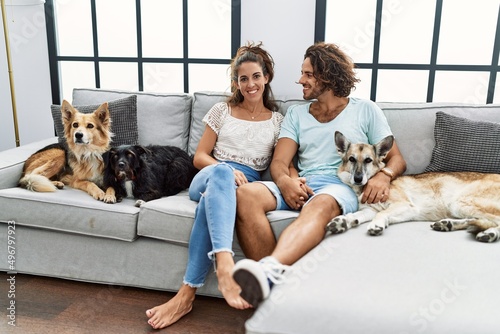 Canvas Print Man and woman couple smiling confident sitting on sofa with dogs at home