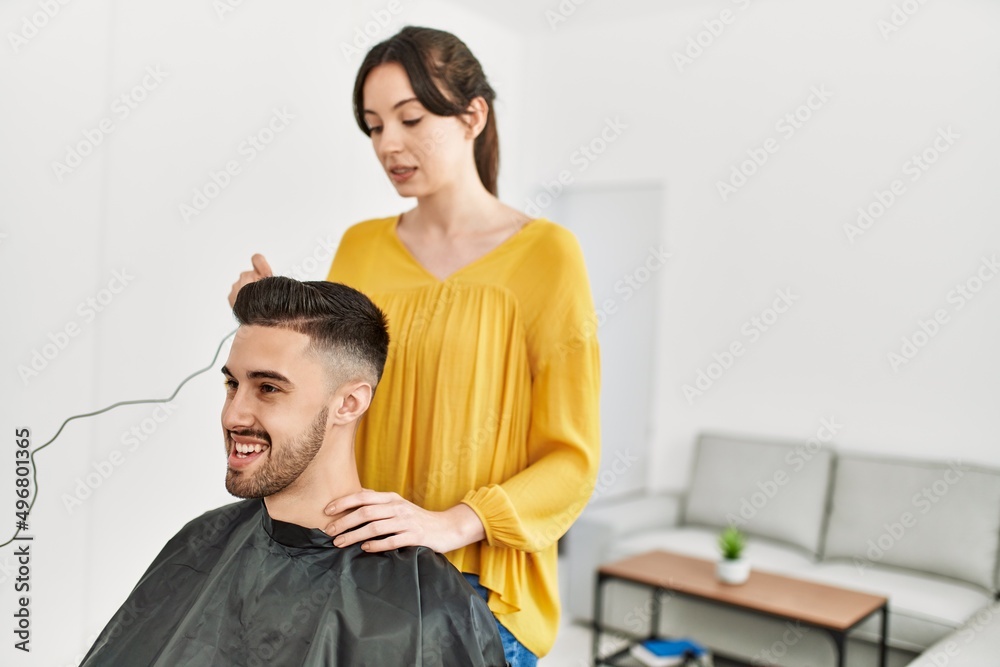 Young hispanic hairdresser woman cutting man's hair using electric razor machine at beauty center. Young hispanic hairdresser woman cutting man's hair using electric razor machine at beauty center.
