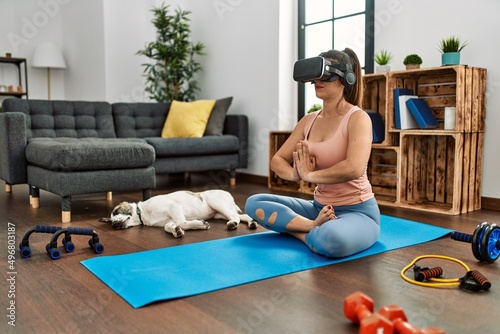 Young woman having online yoga class using vr goggles at home