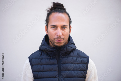 Foto serious young man in sleeveless jacket by white background