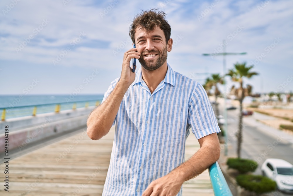 Young hispanic man smiling happy talking on the smartphone at the promenade.
