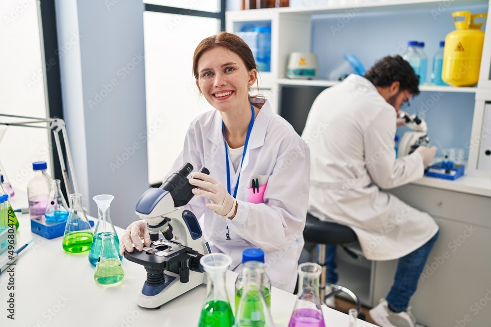 Young two people working at scientist laboratory looking positive and happy standing and smiling with a confident smile showing teeth Young two people working at scientist laboratory looking positive and happy standing and smiling with a confident smile showing teeth