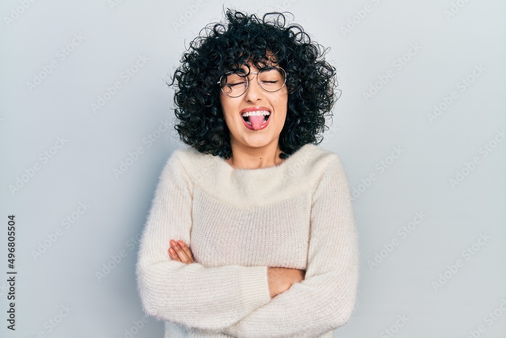 Young middle east woman with arms crossed gesture sticking tongue out happy with funny expression. Young middle east woman with arms crossed gesture sticking tongue out happy with funny expression.