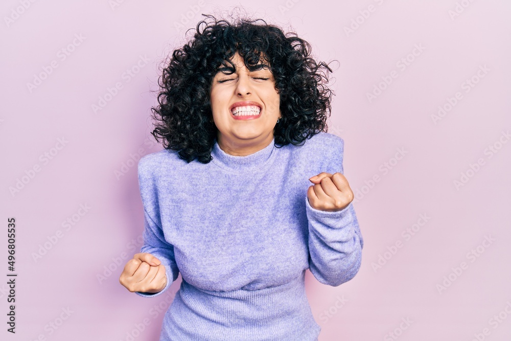 Young middle east woman wearing casual clothes very happy and excited doing winner gesture with arms raised, smiling and screaming for success. celebration concept. Young middle east woman wearing casual clothes very happy and excited doing winner gesture with arms raised, smiling and screaming for success. celebration concept.