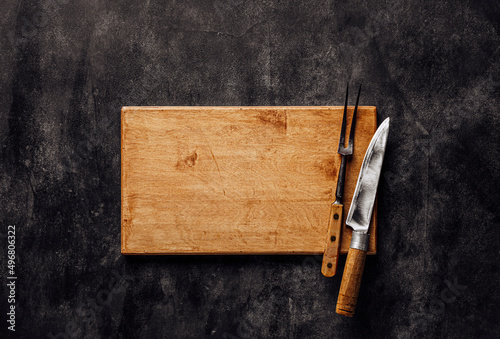 Butcher. Vintage meat knife and fork on cutting board over stone background