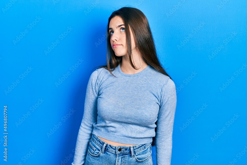 Young brunette teenager wearing casual sweater smiling looking to the side and staring away thinking. Young brunette teenager wearing casual sweater smiling looking to the side and staring away thinking.