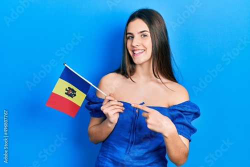 Young brunette teenager holding moldova flag smiling happy pointing with hand and finger