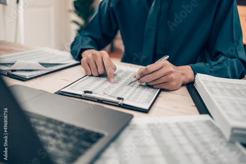 Investors working on desk office and finger  pointing to check tracking cost, balance, projit and  currency. Accounting and  Financial concept. photo