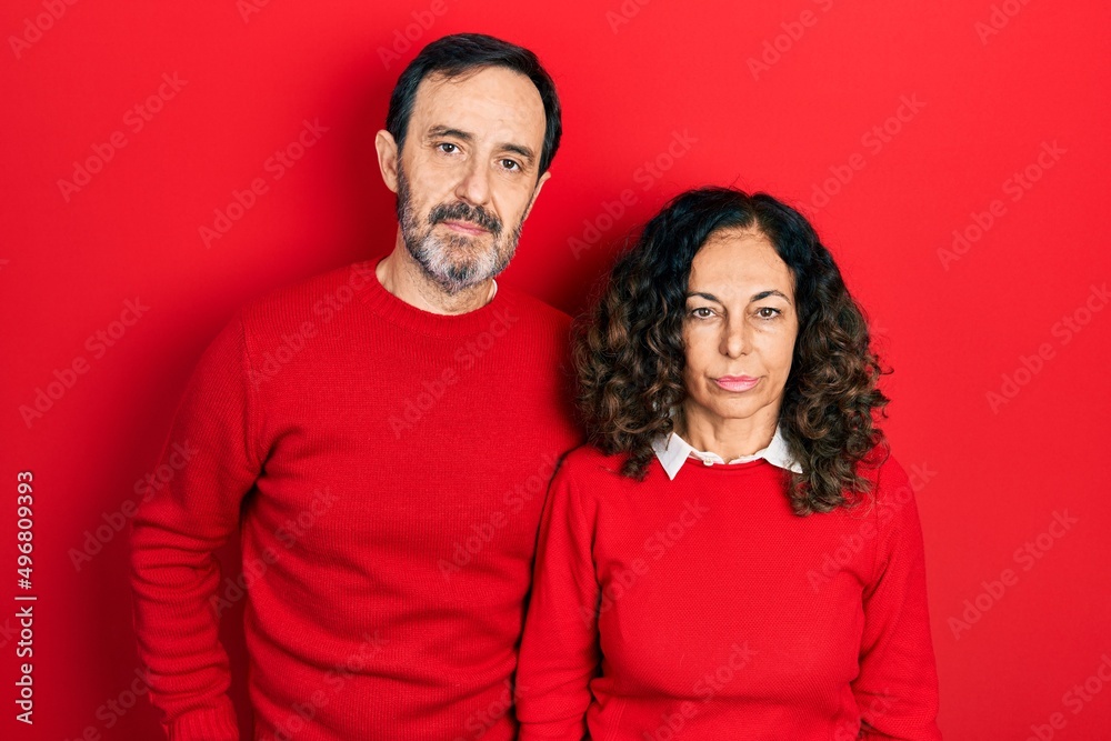 Middle age couple of hispanic woman and man hugging and standing together relaxed with serious expression on face. simple and natural looking at the camera. Middle age couple of hispanic woman and man hugging and standing together relaxed with serious expression on face. simple and natural looking at the camera.