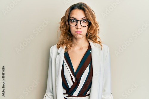 Εκτύπωση καμβά Young caucasian woman wearing business style and glasses puffing cheeks with funny face