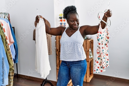 Young african american woman customer holding clothes of rack at clothing store