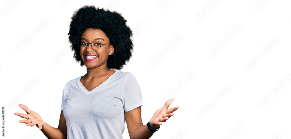 Young african american woman wearing casual white t shirt smiling cheerful with open arms as friendly welcome, positive and confident greetings