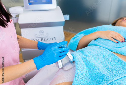 Beautician therapist applying cryolipolysis treatment in beauty salon.