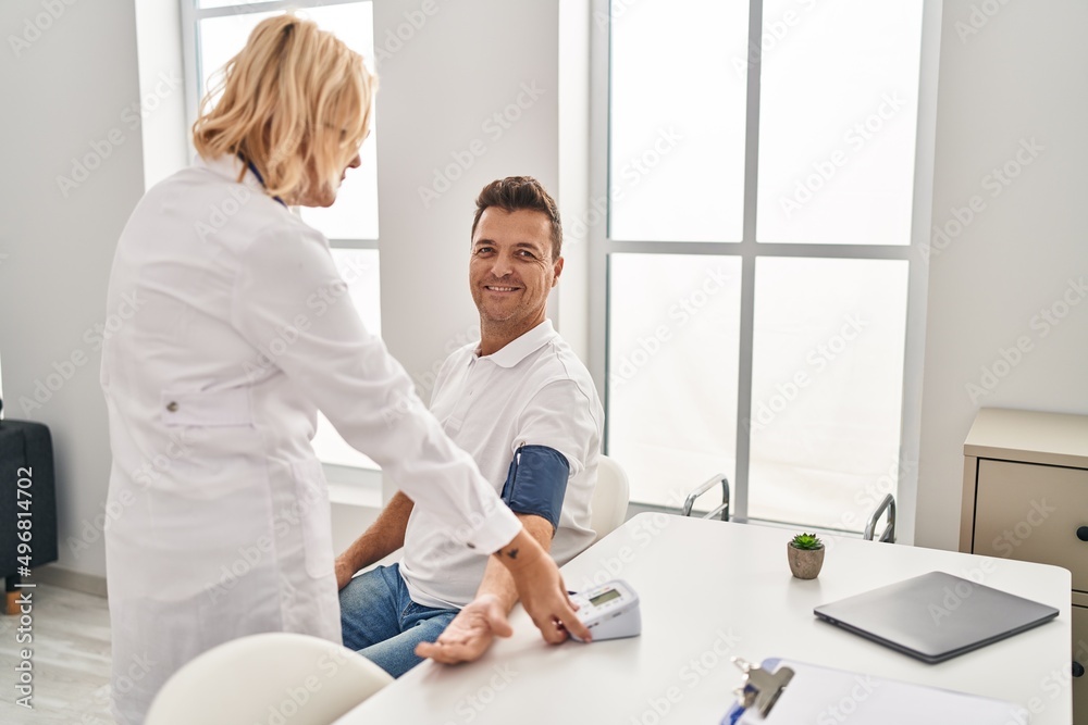 Middle age man and woman doctor and patient using tensiometer having medical consultation at clinic