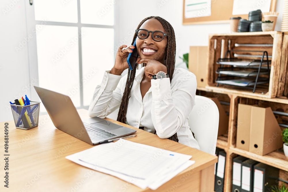 Black woman with braids working at the office speaking on the phone with hand on chin thinking about question, pensive expression. smiling and thoughtful face. doubt concept. Black woman with braids working at the office speaking on the phone with hand on chin thinking about question, pensive expression. smiling and thoughtful face. doubt concept.