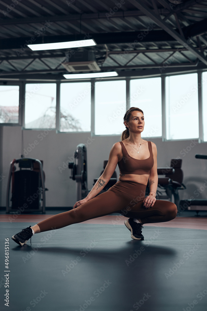 Fototapeta premium Pretty woman working out in a gym. Adult lady with beautiful shaped body.
