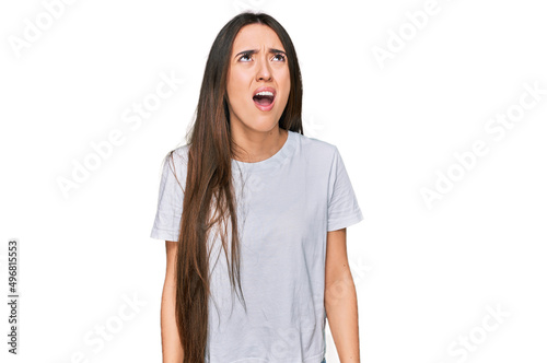 Young hispanic girl wearing casual white t shirt angry and mad screaming frustrated and furious, shouting with anger. rage and aggressive concept. © Krakenimages.com