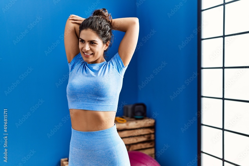 Young latin woman smiling confident stretching at sport center