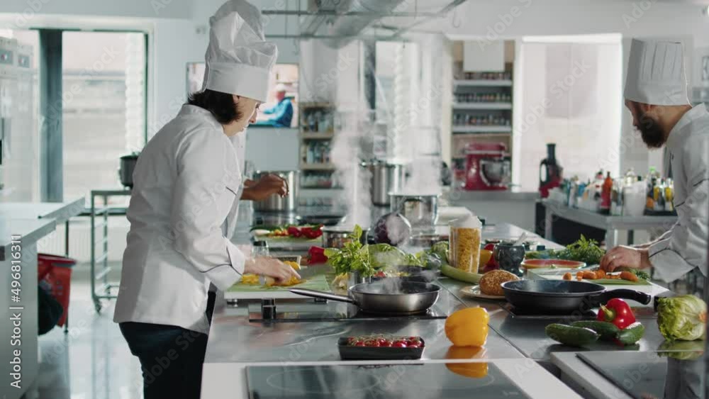 Female cook chopping bell peppers on cutting board to make professional cuisine dish. Woman chef cooking gourmet meal with organic food and vegetables, preparing recipe ingredients.
