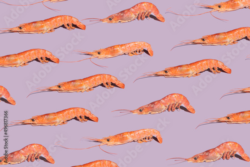 Modern seafood minimal concept. Pattern made of many fresh organic pink prawns against purple background
