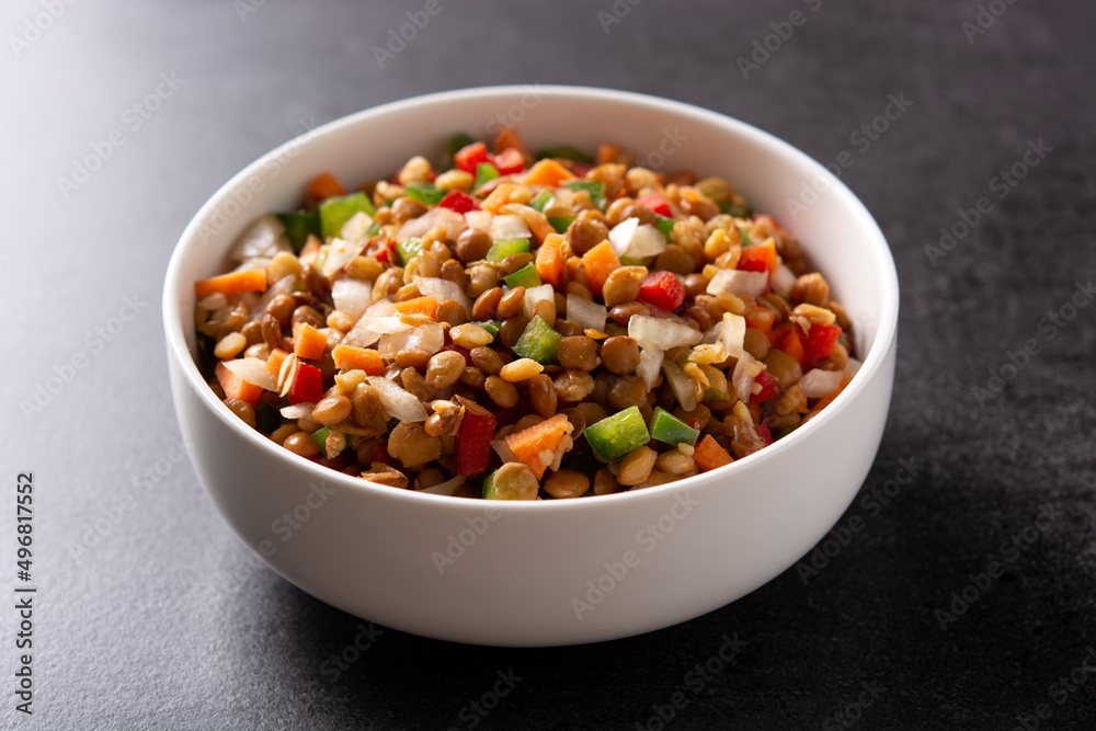 Lentil salad with peppers,onion and carrot in a bowl on black background Lentil salad with peppers,onion and carrot in a bowl on black background