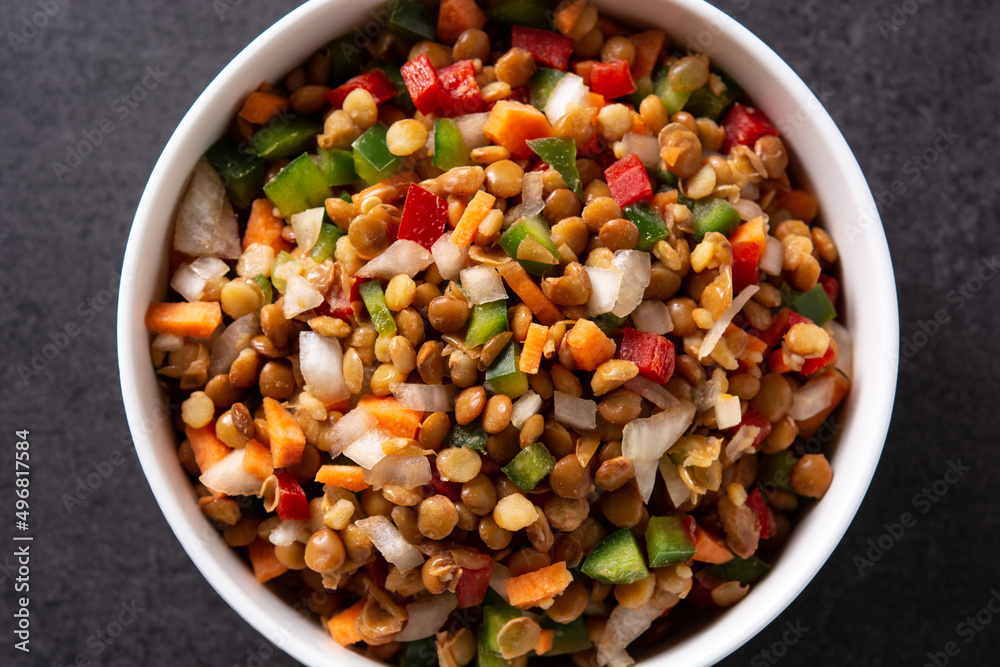 Lentil salad with peppers,onion and carrot in a bowl on black background Lentil salad with peppers,onion and carrot in a bowl on black background