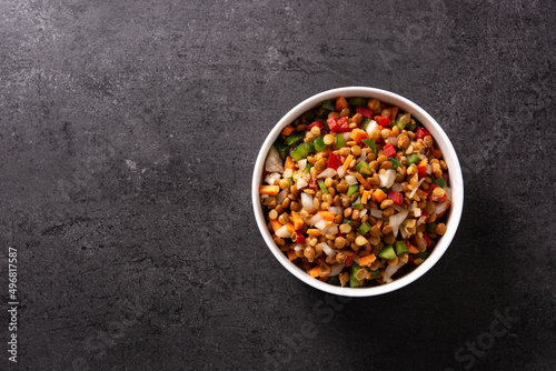 Lentil salad with peppers,onion and carrot in a bowl on black background. Top view. Copy space