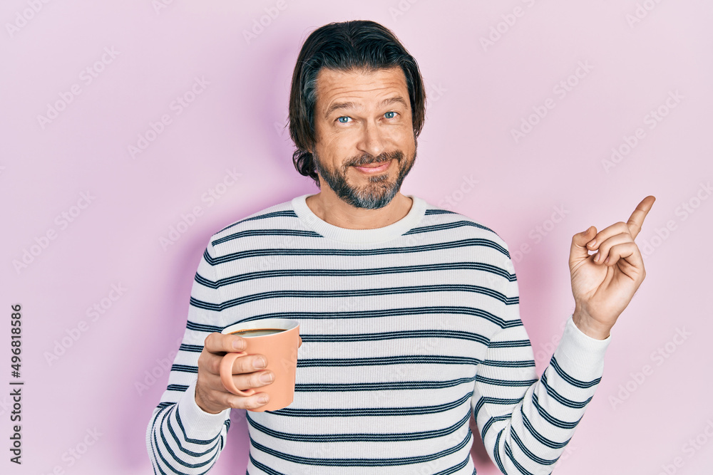 Fototapeta premium Middle age caucasian man drinking a cup of coffee smiling happy pointing with hand and finger to the side