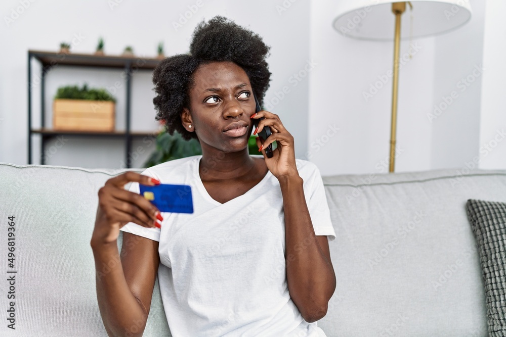 Young african american woman speaking on the phone holding credit card at home Young african american woman speaking on the phone holding credit card at home
