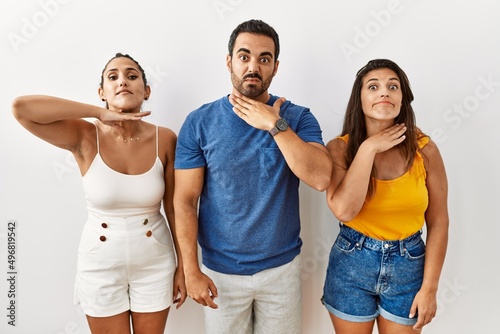 Group of young hispanic people standing over isolated background cutting throat with hand as knife  threaten aggression with furious violence