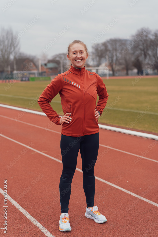 Obraz premium Young fitness woman running at a track and field stadium