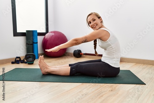 Young caucasian woman smiling confident stretching at sport center