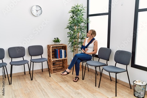 Young caucasian woman wearing sling on arm for accident sitting on chair at waiting room © Krakenimages.com