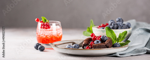 Banner with warm chocolate pudding lava cake with fondant centre, red currants, bleuberry and mint leaves on gray background photo