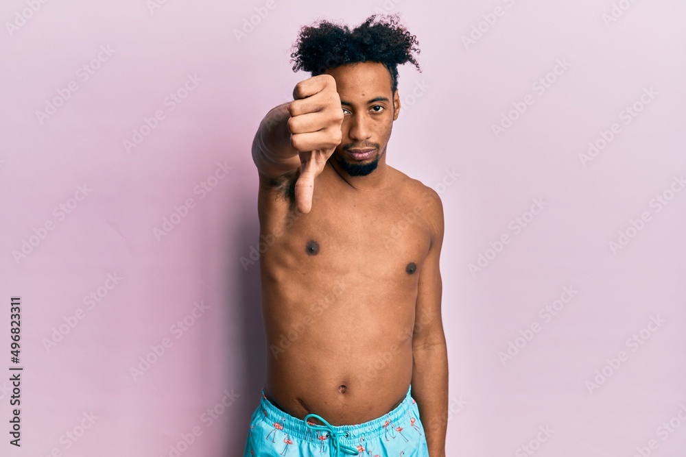 Fototapeta premium Young african american man with beard wearing swimsuit looking unhappy and angry showing rejection and negative with thumbs down gesture. bad expression.