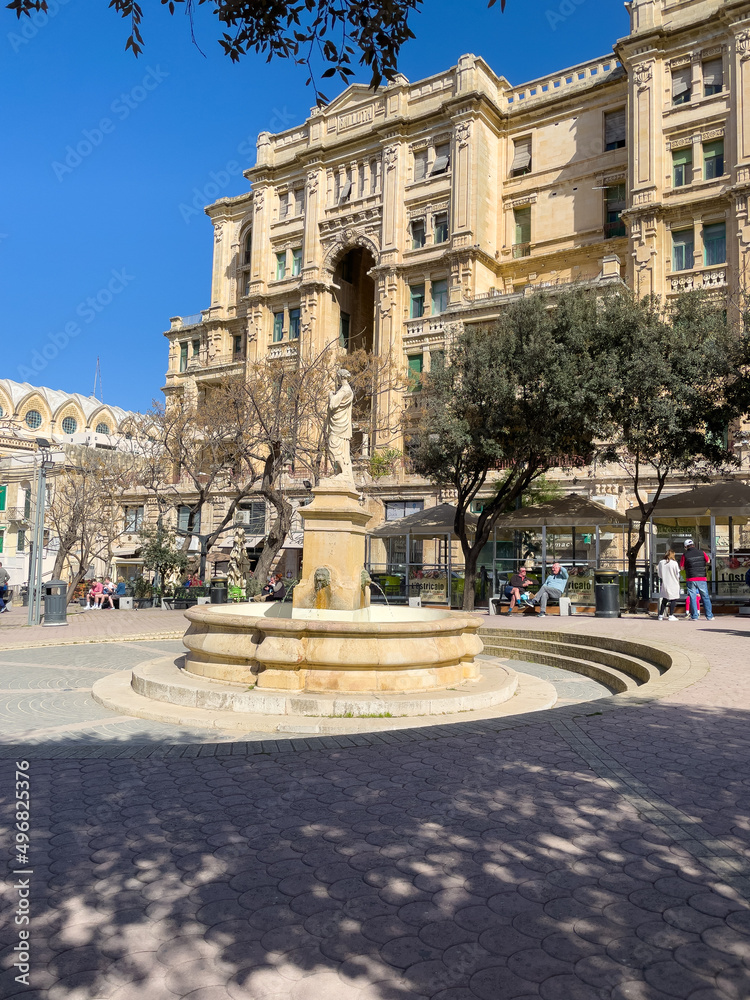 The fountain in Balluta Square overlooked by the Art Nouveau style Balluta Buildings - St Julians, Malta.