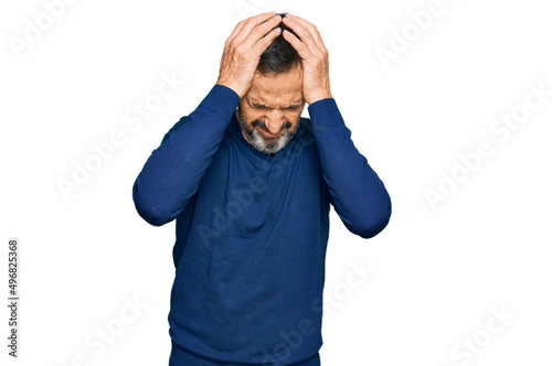 Middle age hispanic man wearing casual clothes suffering from headache desperate and stressed because pain and migraine. hands on head.