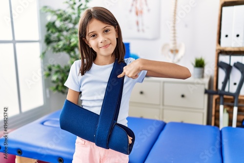 Young hispanic girl wearing arm on sling at rehabilitation clinic pointing finger to one self smiling happy and proud Free Download Young hispanic girl wearing arm on sling at rehabilitation clinic pointing finger to one self smiling happy and proud - GFXLoad