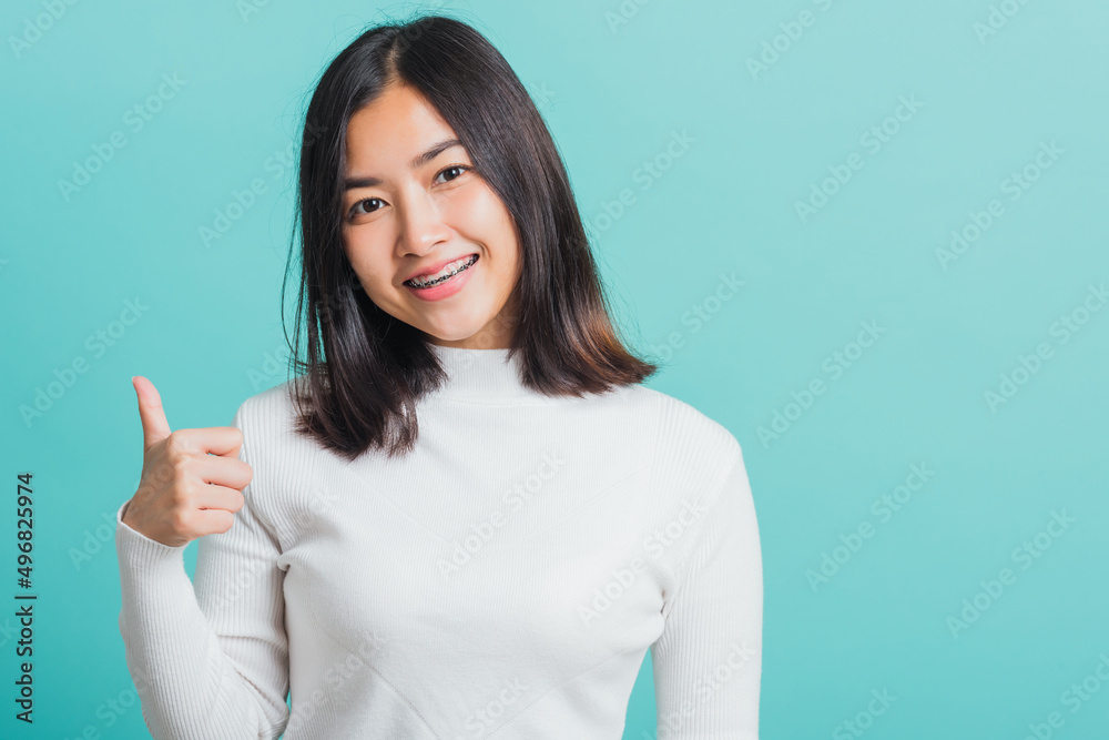 Young beautiful Asian woman cheerful smiling showing finger thumb up, Portrait happy female using showing like the gesture for good sign, studio shot isolated on a blue background Young beautiful Asian woman cheerful smiling showing finger thumb up, Portrait happy female using showing like the gesture for good sign, studio shot isolated on a blue background